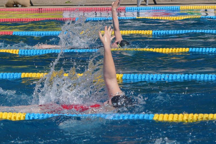 Man sieht eine Nahaufnahme von zwei Schwimmer:innen, die in Rückenlage schwimmen.